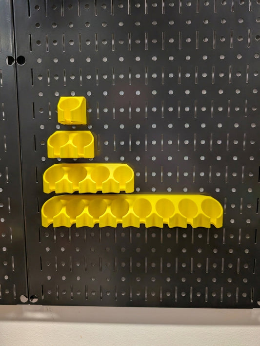Four bright yellow pegboard holders of varying sizes mounted on a black metal Wall Control pegboard.